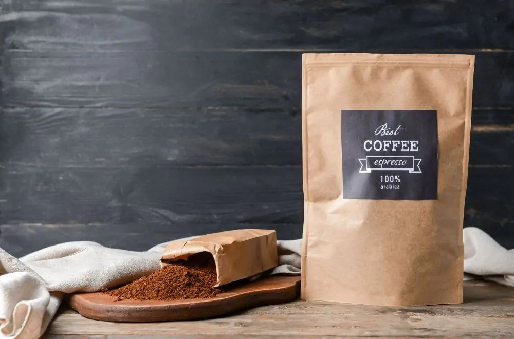 Bags with coffee powder on wooden background