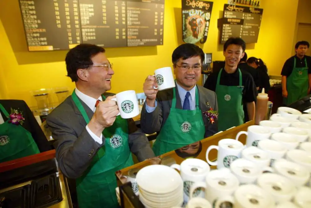Starbucks employees laughing while some are holding Starbucks mug