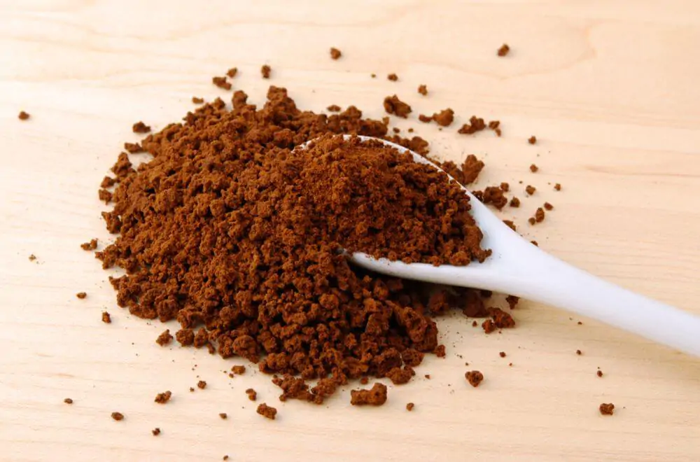 Ceramic spoon in a pile of instant coffee powder