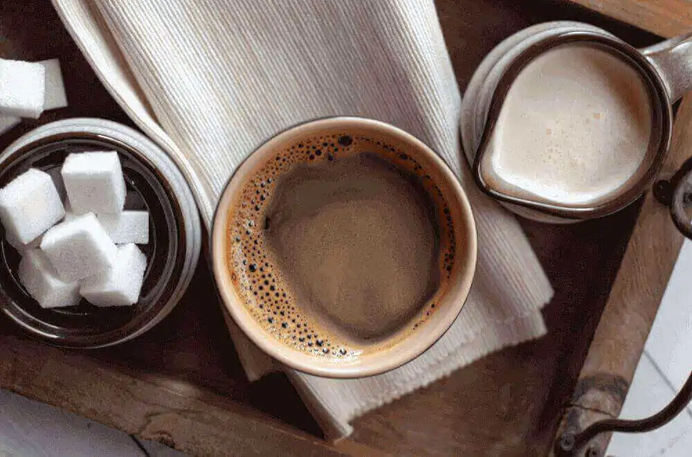 Mug of coffee with creamer and sugar cubes