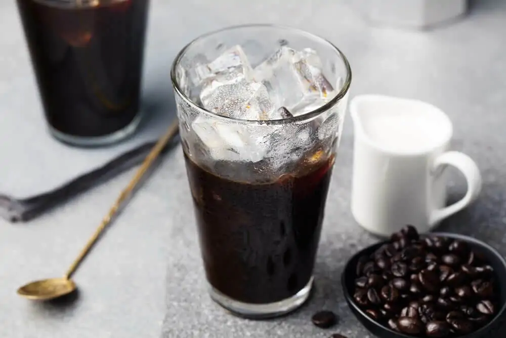 Ice coffee in a tall glass and coffee beans - how to grind coffee beans for cold brewing