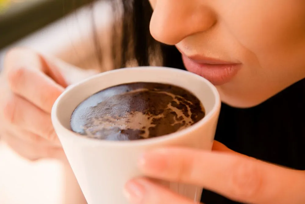Young woman enjoying coffee aroma 