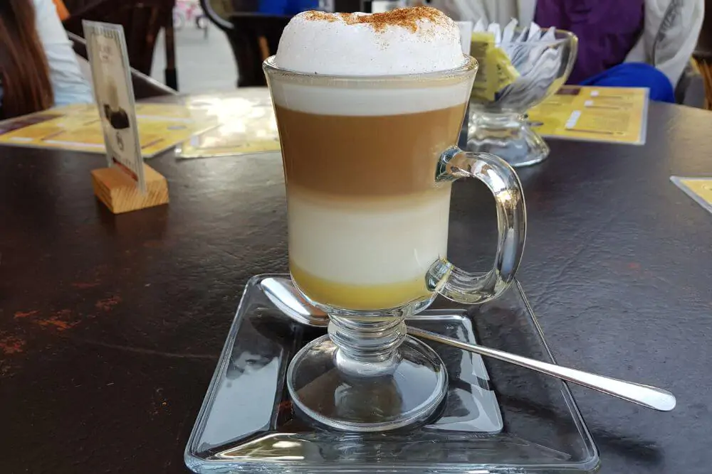Having a cup of vanilla cappuccino on a glass plate