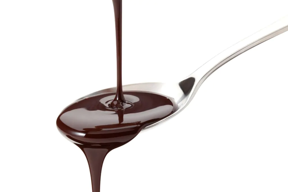 Flowing chocolate on a spoon over white background