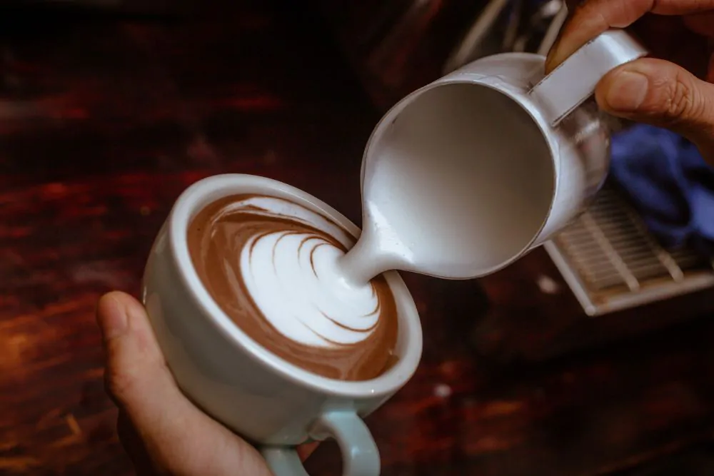 Barista making a cup of hot chocolate art with steamed milk