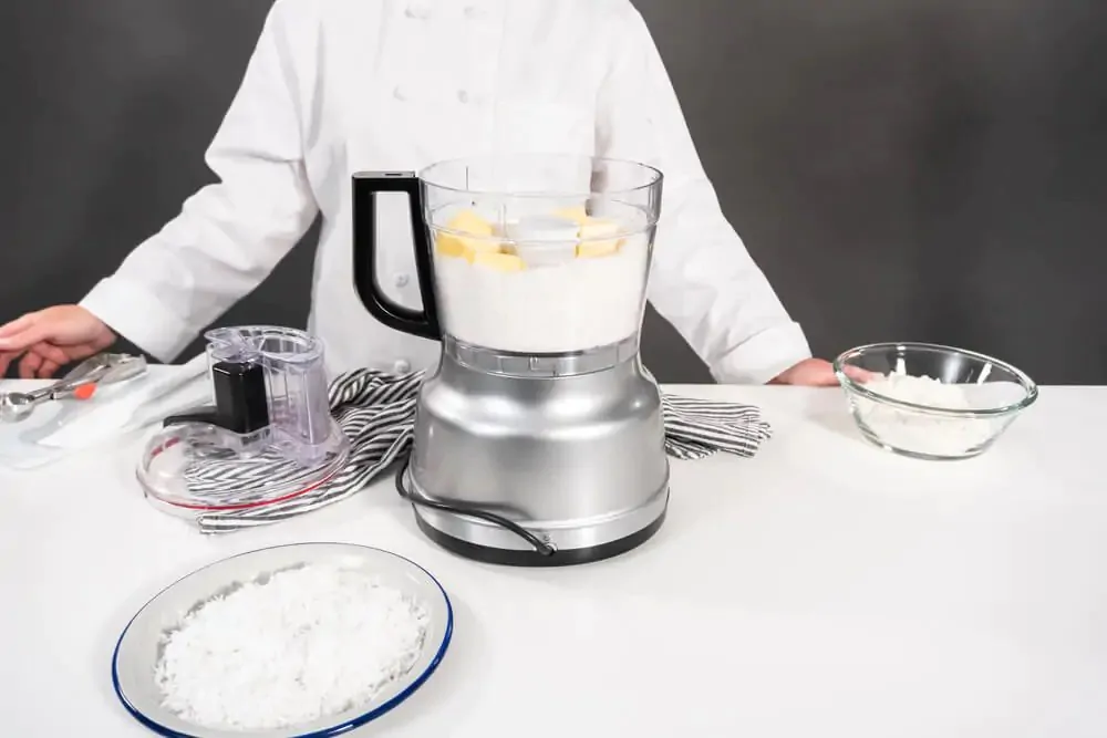 A chef with food processor on top of white table