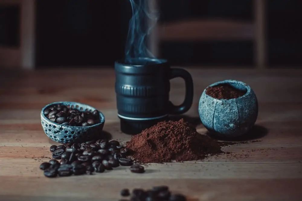 Coffee beans, ground coffee and coffee cup on table