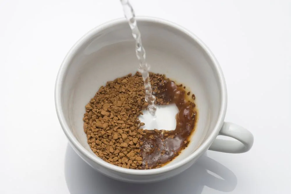 Pouring hot water to a cup with instant coffee