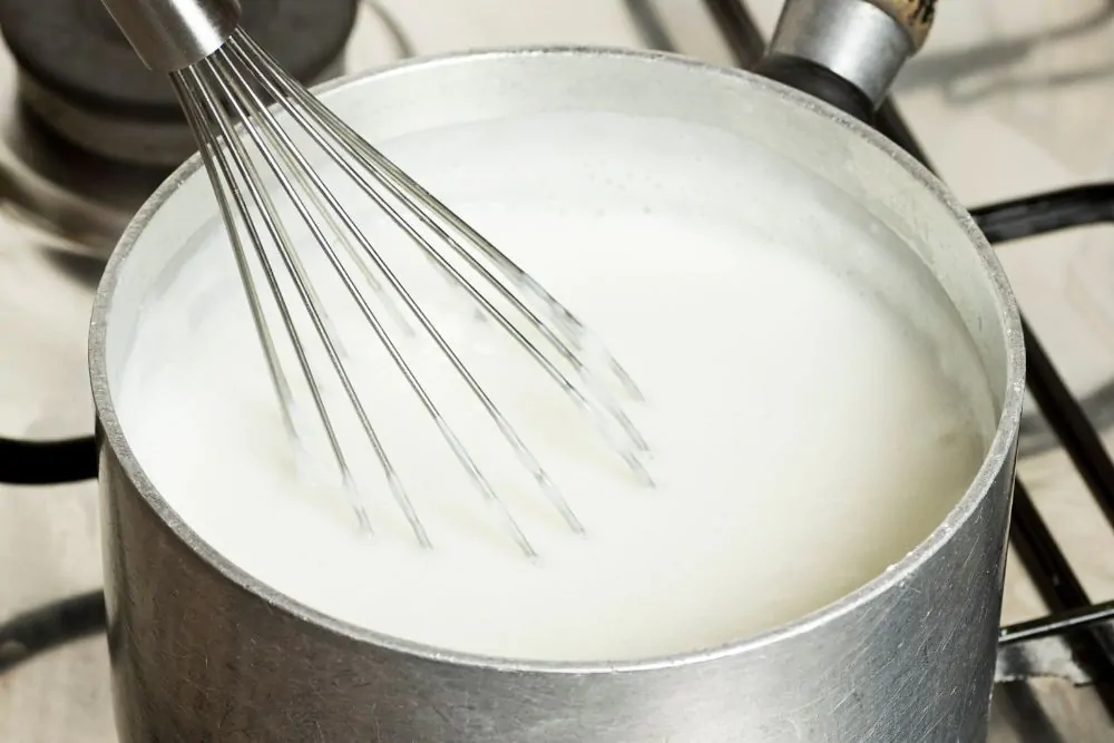 heating up milk on a stove and stirring with whisk