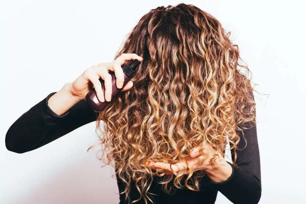 Woman applying spray to curly hair