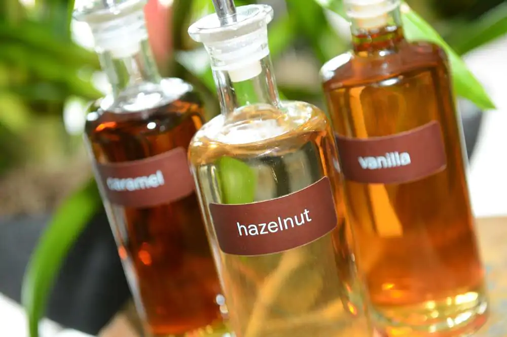 Pretty glass bottles containing hazelnut, vanilla and caramel coffee syrups for flavoring a drink